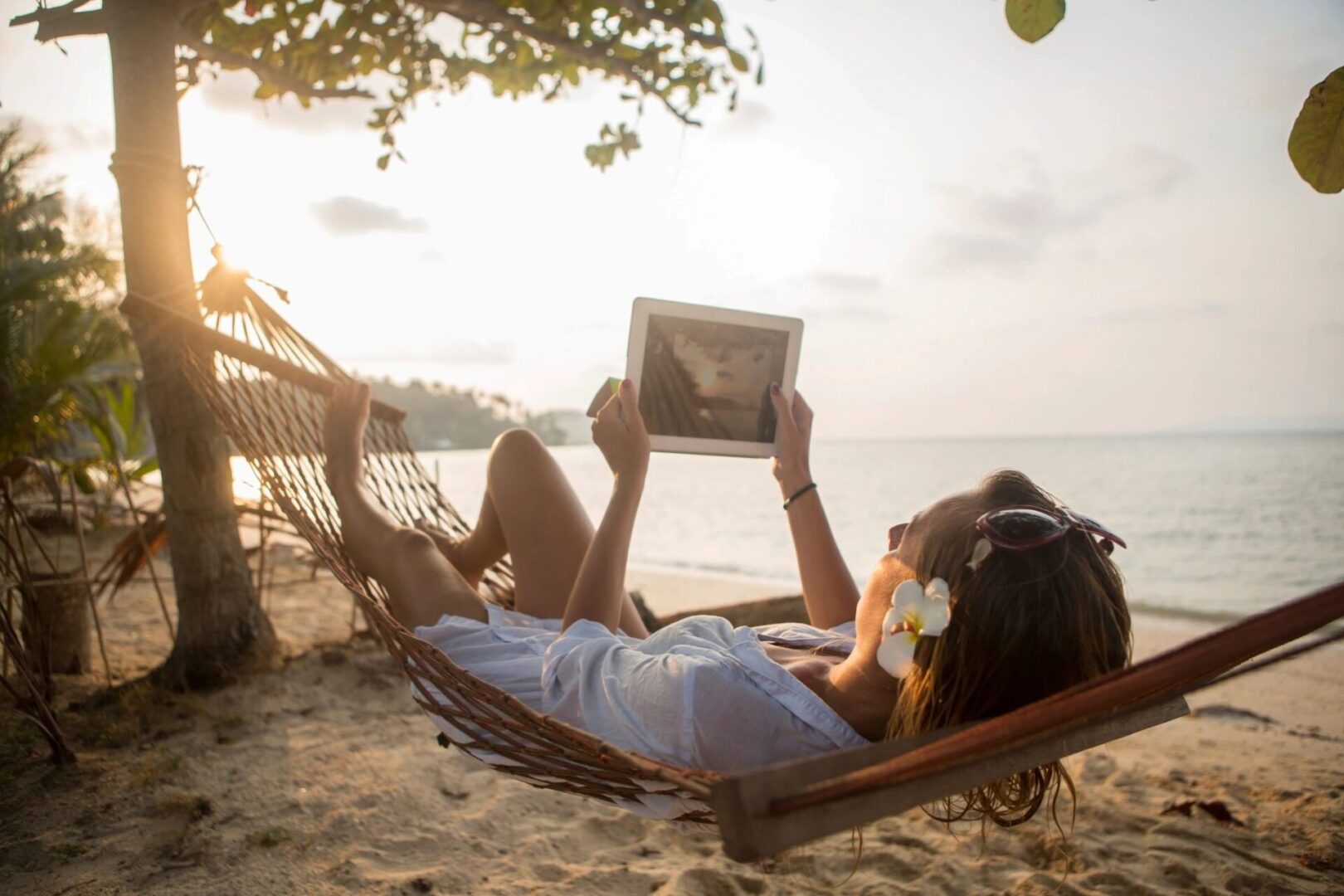 a woman relaxing by the beach and looking at a tablet